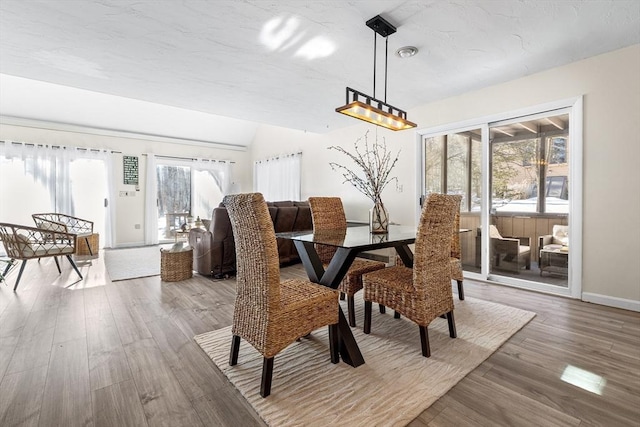 dining space with lofted ceiling, baseboards, a wealth of natural light, and wood finished floors