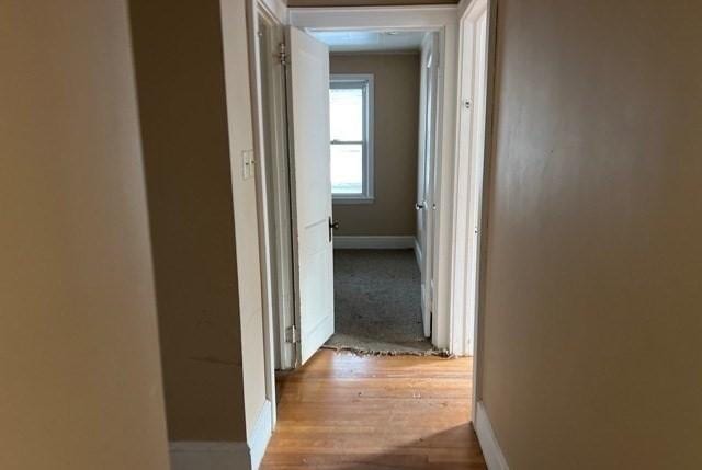 corridor with baseboards and wood finished floors