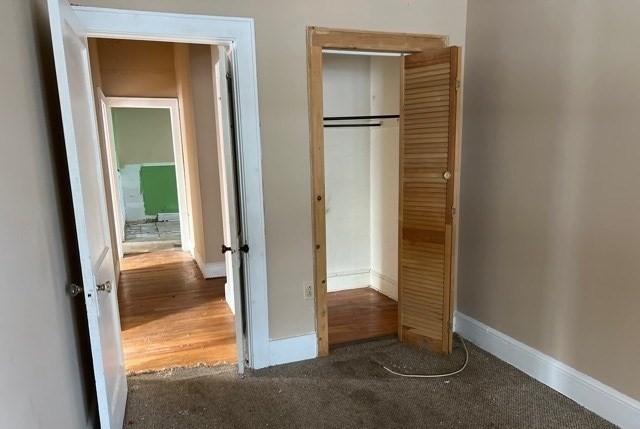 unfurnished bedroom with a closet, baseboards, and carpet