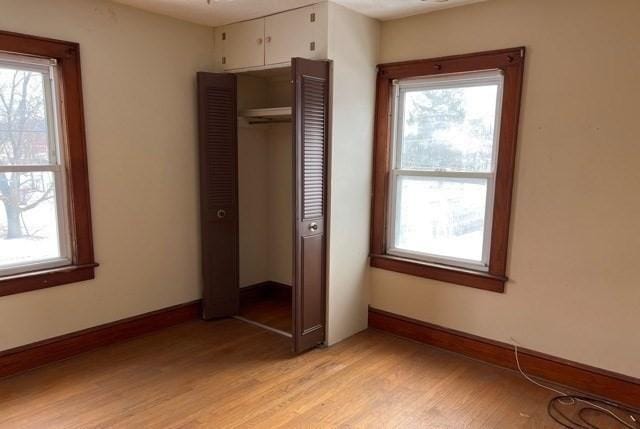 unfurnished bedroom with a closet, baseboards, and light wood-style floors