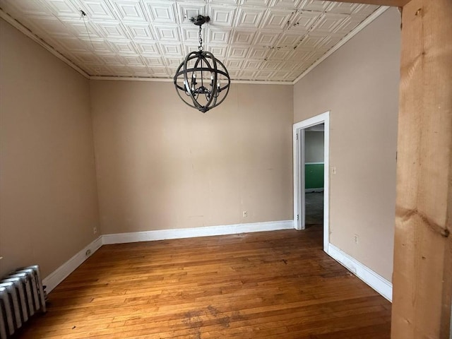 unfurnished dining area featuring baseboards, an ornate ceiling, radiator, and wood finished floors