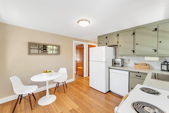 kitchen with light countertops, baseboards, light wood-type flooring, and white appliances