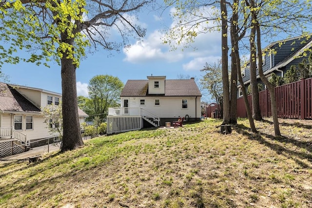 back of property with a yard, stairway, a wooden deck, and a fenced backyard
