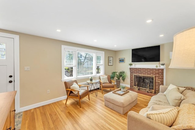living room with a fireplace, baseboards, light wood finished floors, radiator heating unit, and recessed lighting