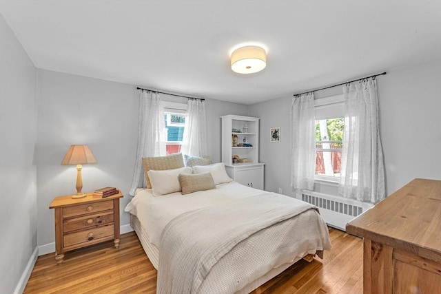 bedroom featuring baseboards, radiator, and light wood-type flooring