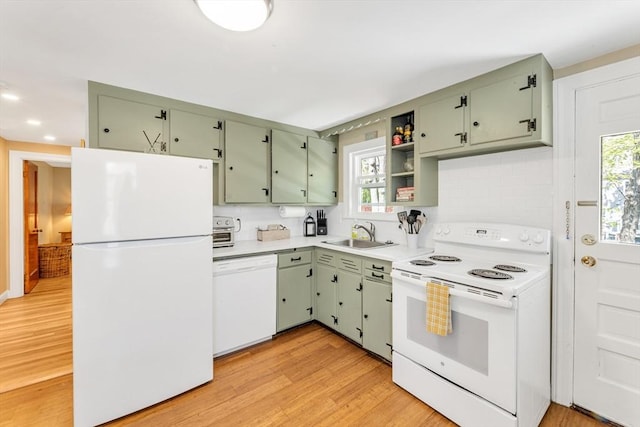 kitchen featuring a sink, green cabinetry, white appliances, and light wood-style flooring