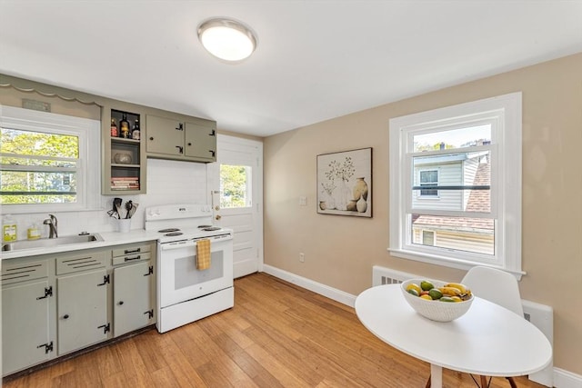 kitchen with baseboards, white electric range, tasteful backsplash, a sink, and light wood-style flooring