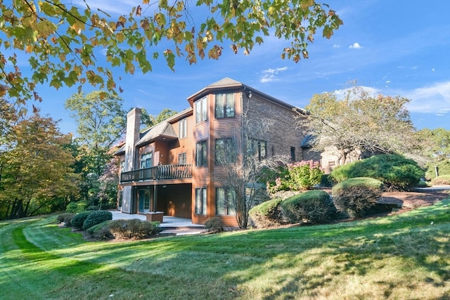 rear view of property with a yard and a balcony