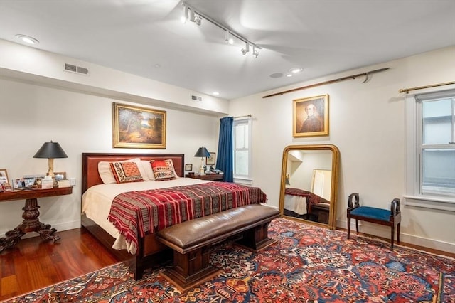 bedroom with dark hardwood / wood-style flooring and track lighting