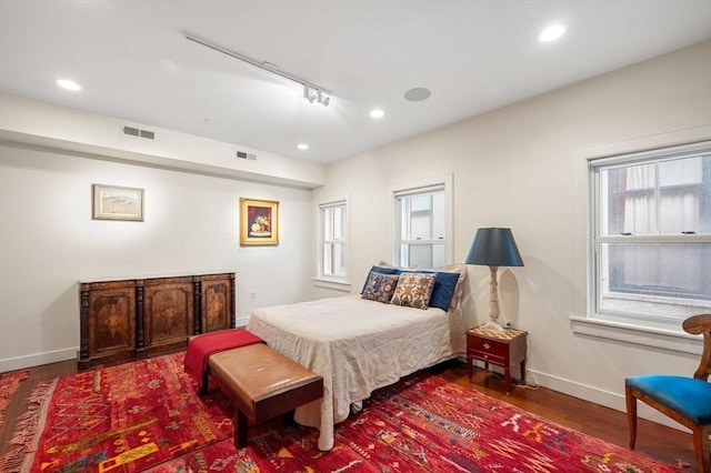 bedroom with hardwood / wood-style flooring, rail lighting, and multiple windows