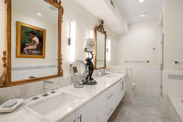 bathroom with vanity, toilet, an enclosed shower, and tile walls