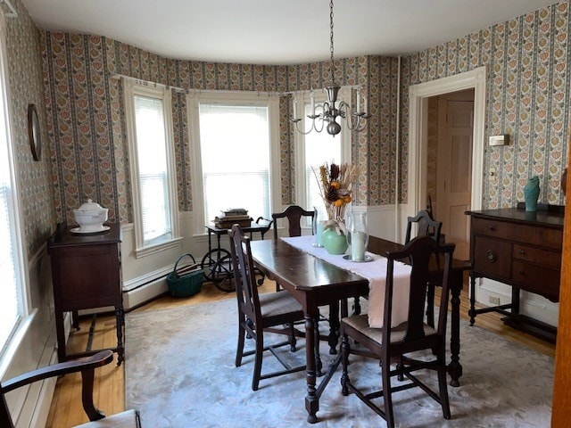 dining space with a chandelier, wood-type flooring, and a baseboard heating unit