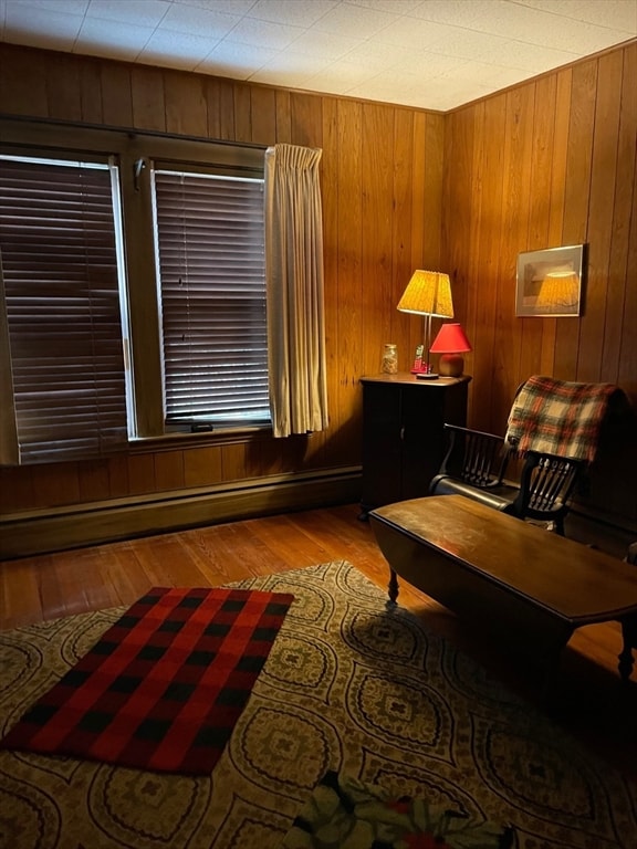 living area featuring a baseboard heating unit, light hardwood / wood-style flooring, and wooden walls