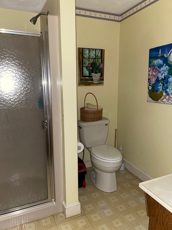 bathroom with a shower with shower door, vanity, toilet, and a textured ceiling