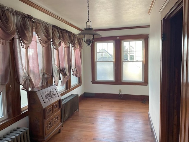 interior space featuring radiator, hardwood / wood-style floors, a textured ceiling, and ornamental molding