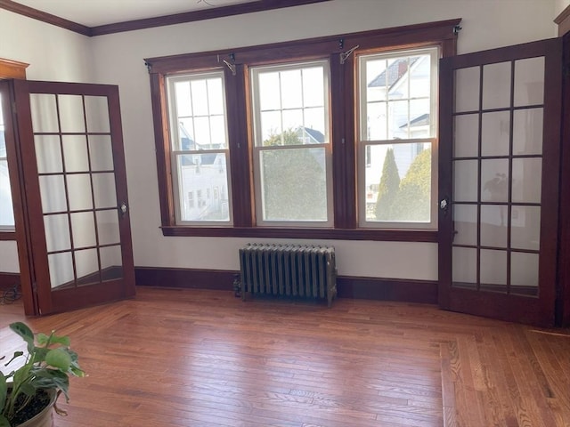 spare room featuring radiator, plenty of natural light, and hardwood / wood-style flooring