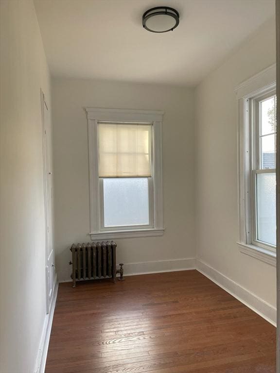 empty room featuring radiator and dark wood-type flooring