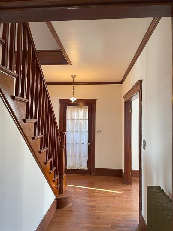 entrance foyer with radiator heating unit, hardwood / wood-style floors, and ornamental molding