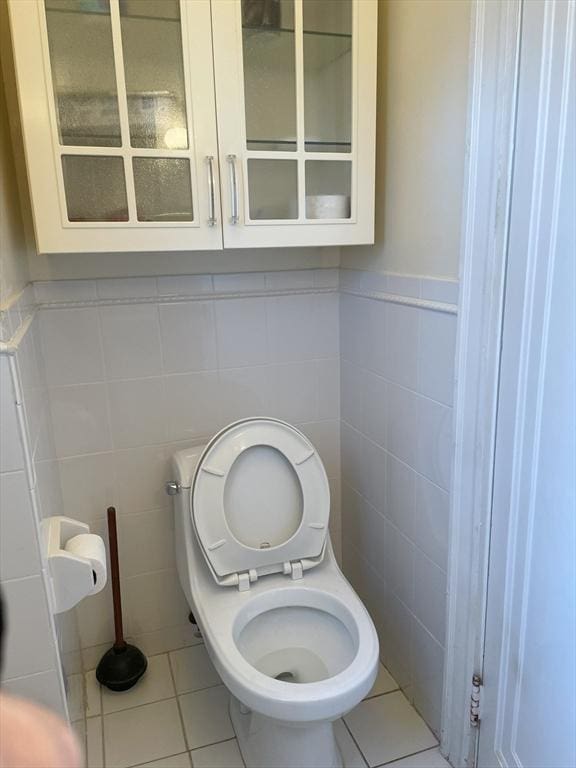 bathroom with tile patterned floors, toilet, and tile walls