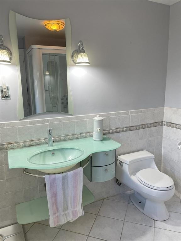 bathroom with tile patterned floors, sink, toilet, and tile walls