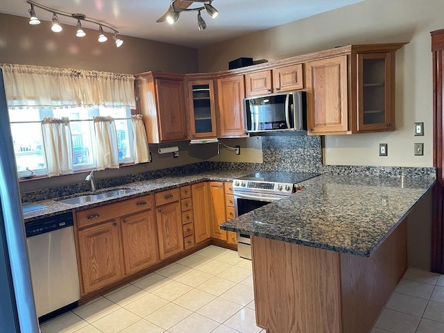 kitchen featuring sink, stainless steel appliances, kitchen peninsula, dark stone counters, and light tile patterned floors