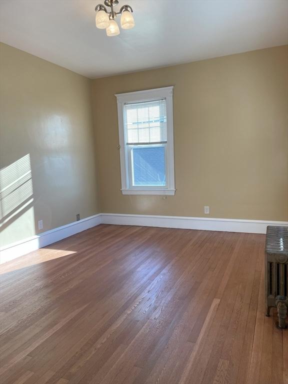 spare room featuring wood-type flooring and a notable chandelier