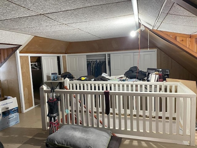 additional living space featuring wooden walls, concrete flooring, and lofted ceiling