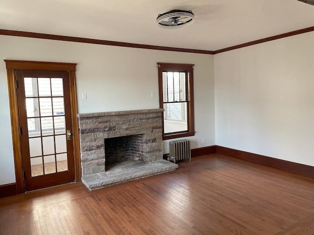 unfurnished living room featuring hardwood / wood-style flooring, crown molding, radiator heating unit, and a fireplace