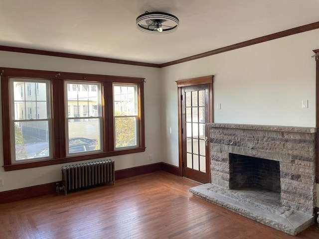 unfurnished living room featuring hardwood / wood-style floors, ornamental molding, a fireplace, and radiator