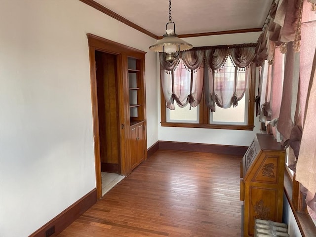 unfurnished dining area featuring dark wood-type flooring and ornamental molding