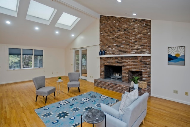 living room featuring hardwood / wood-style flooring, beamed ceiling, a brick fireplace, high vaulted ceiling, and a skylight