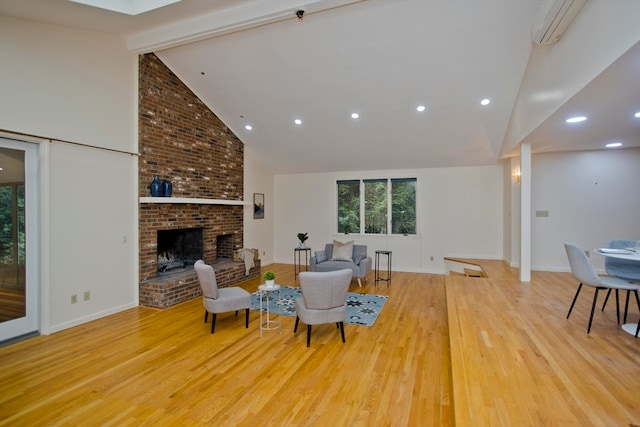 living room with high vaulted ceiling, a wall mounted air conditioner, beamed ceiling, a fireplace, and light hardwood / wood-style floors