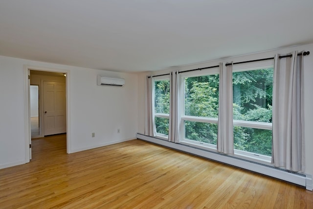 unfurnished room with a wall mounted air conditioner, a baseboard radiator, and light wood-type flooring