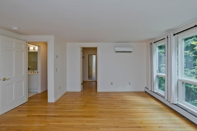 empty room with light hardwood / wood-style floors, a baseboard heating unit, and a wall mounted AC