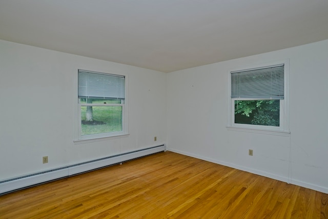 spare room with a baseboard heating unit and light wood-type flooring