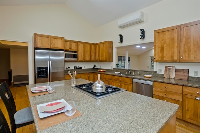 kitchen with appliances with stainless steel finishes, light hardwood / wood-style flooring, a wall mounted AC, and a kitchen breakfast bar