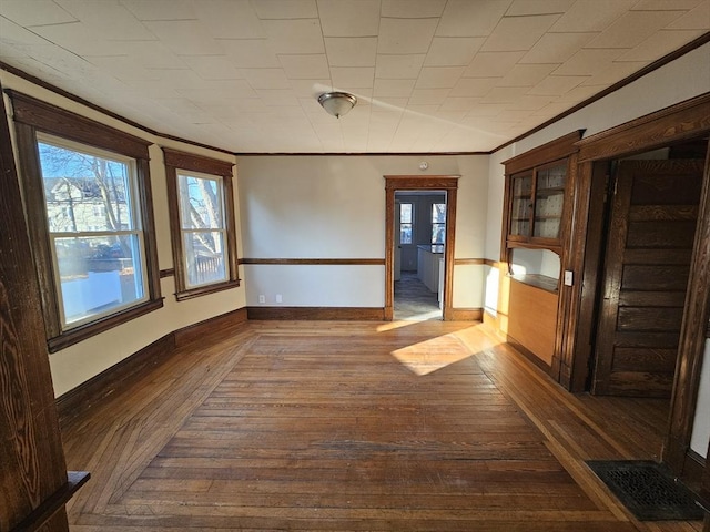 unfurnished dining area with dark hardwood / wood-style flooring and crown molding