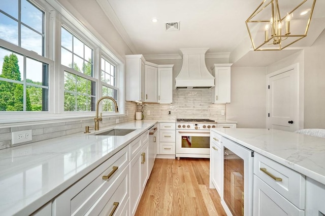 46 Pearl St, Melrose, MA 02176 - kitchen featuring white range with gas cooktop, custom exhaust hood, beverage cooler, light wood-style flooring, and backsplash