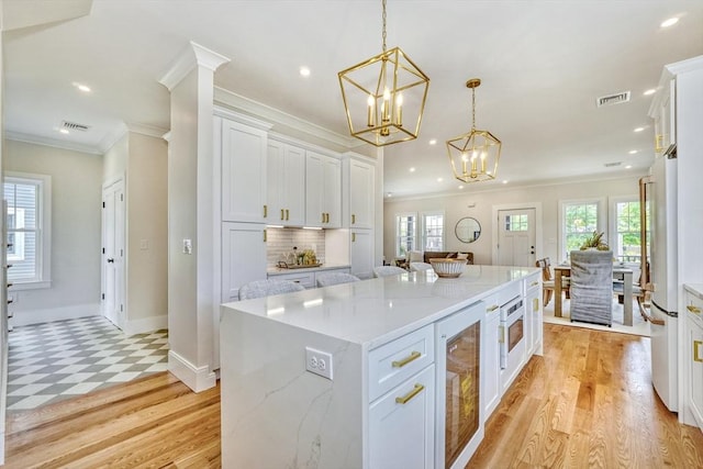 46 Pearl St, Melrose, MA 02176 - kitchen featuring wine cooler, a chandelier, white cabinets, ornamental molding, and a center island