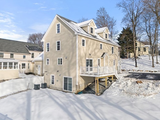 snow covered house with central AC and a wooden deck