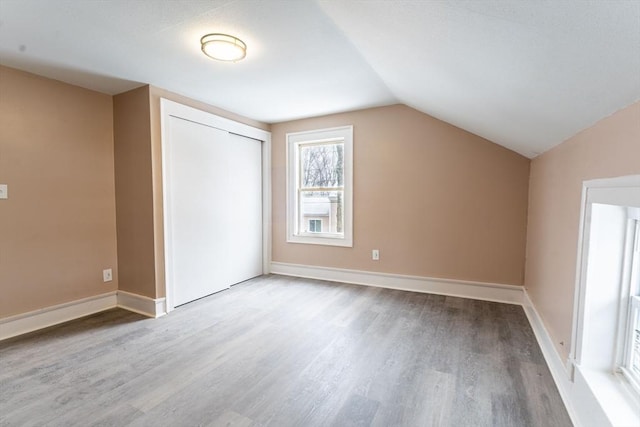 additional living space with baseboards, vaulted ceiling, and wood finished floors