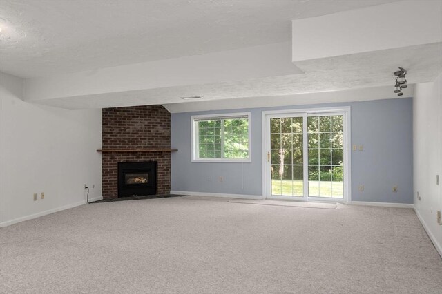 399 Pond St Unit G6, Braintree, MA 02184 - unfurnished living room featuring a textured ceiling, light colored carpet, and a brick fireplace