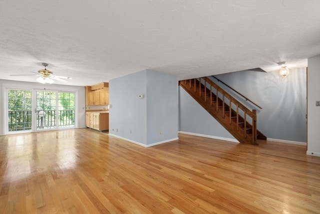 399 Pond St Unit G6, Braintree, MA 02184 - unfurnished living room with light wood-style flooring, stairs, a textured ceiling, and a ceiling fan