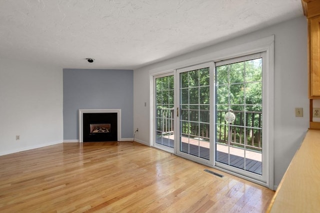 399 Pond St Unit G6, Braintree, MA 02184 - unfurnished living room with light wood-style flooring, a fireplace, and a textured ceiling