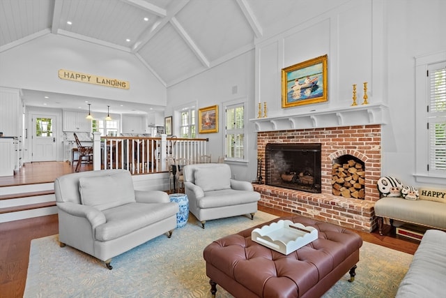 living room with high vaulted ceiling, hardwood / wood-style floors, plenty of natural light, and a fireplace