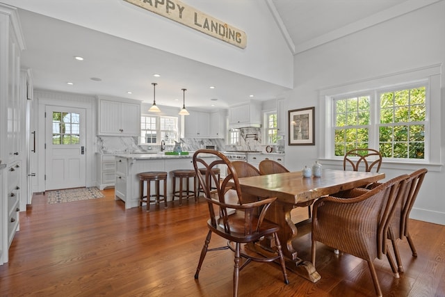 dining space featuring a wealth of natural light, vaulted ceiling, and dark hardwood / wood-style flooring