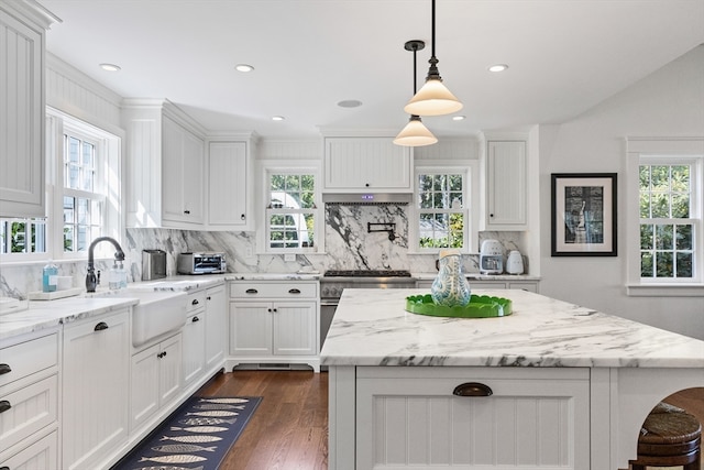 kitchen featuring tasteful backsplash, sink, white cabinetry, a kitchen island, and dark hardwood / wood-style flooring