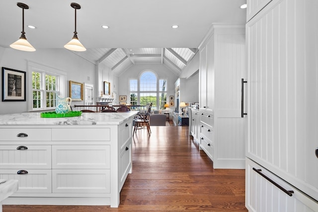 kitchen featuring lofted ceiling with beams, light stone counters, dark wood-type flooring, white cabinets, and decorative light fixtures