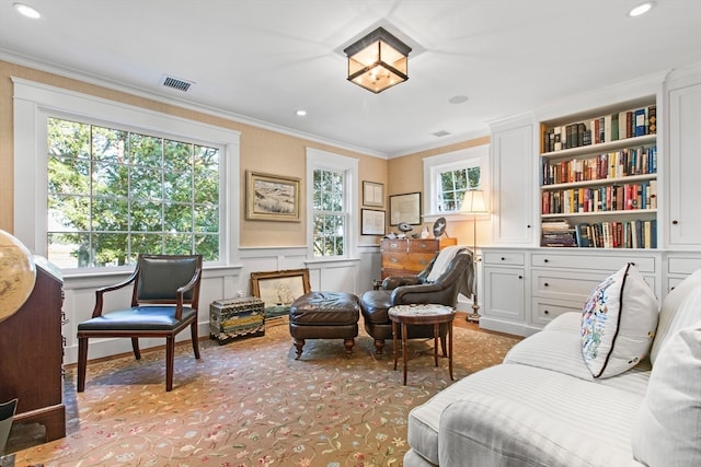 sitting room featuring built in shelves and crown molding