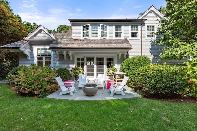 rear view of property with a lawn, a patio, french doors, and a fire pit